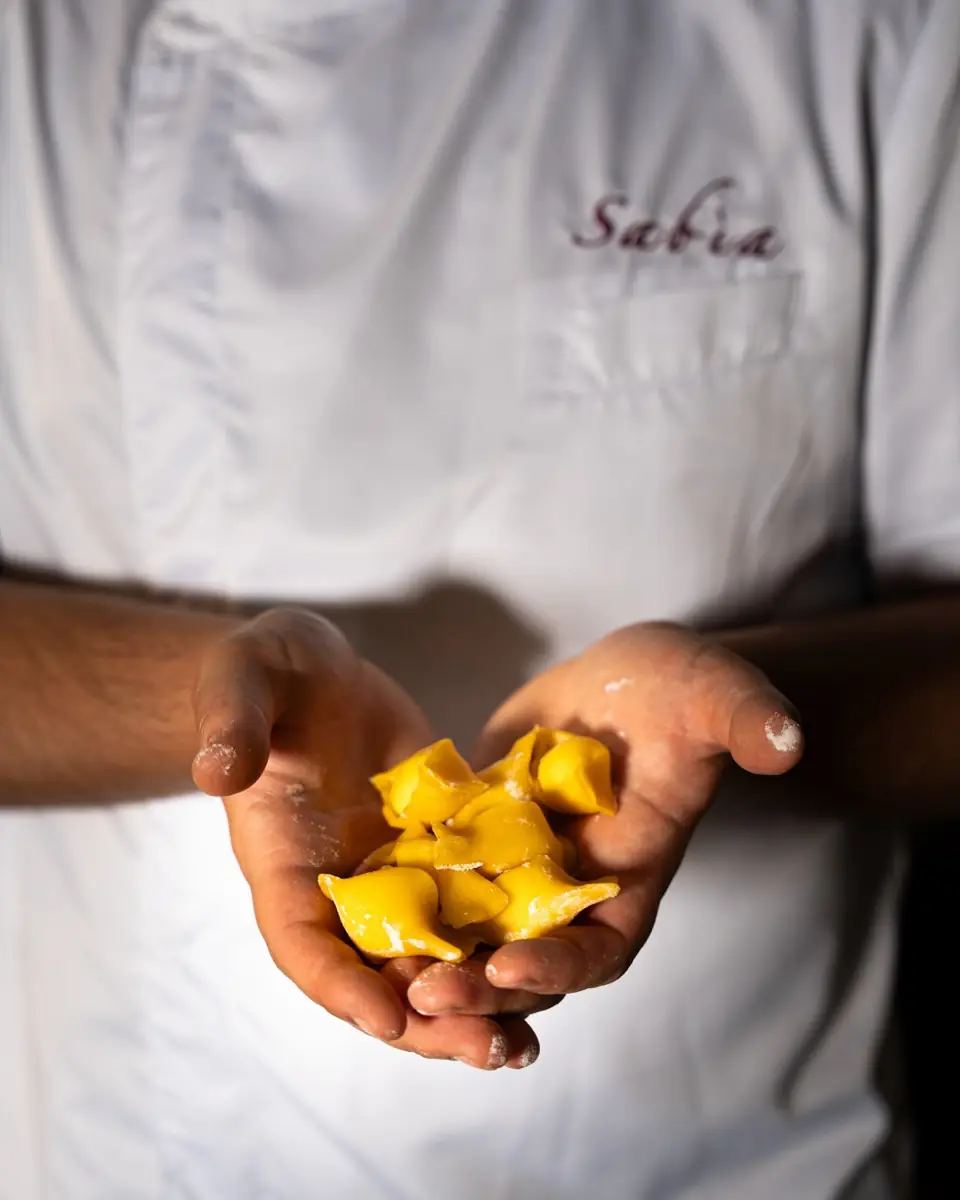 Le mani dello chef con i tortelli di pasta fresca